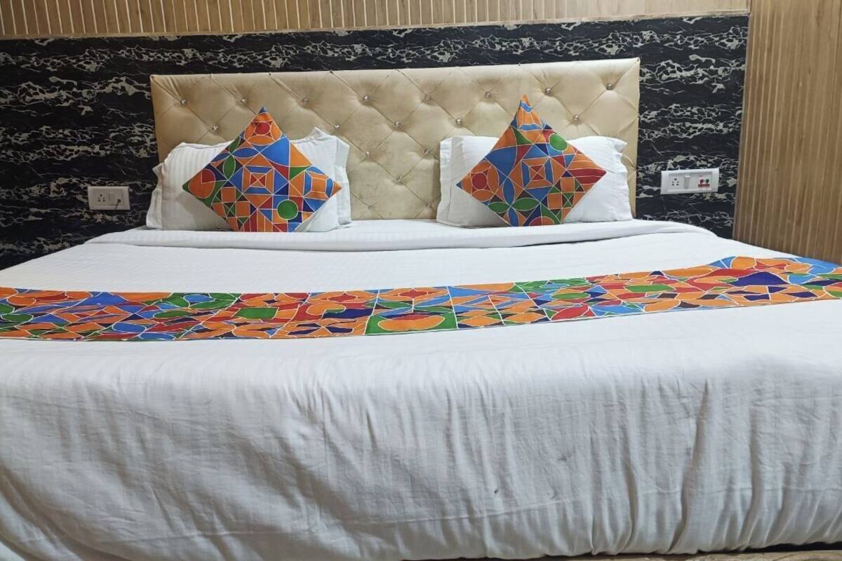 Un lit recouvert d’une couvre-lit blanche et agrémenté de deux coussins décoratifs aux motifs géométriques.