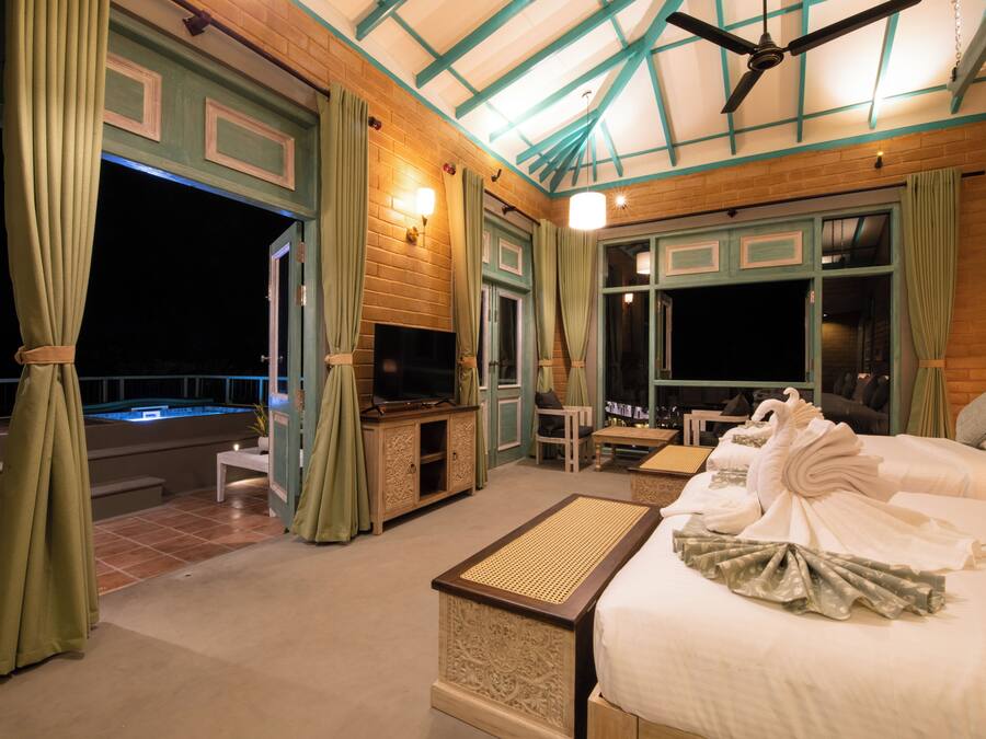 Una habitación bien iluminada con cama, televisor, zona de estar y vistas al exterior.