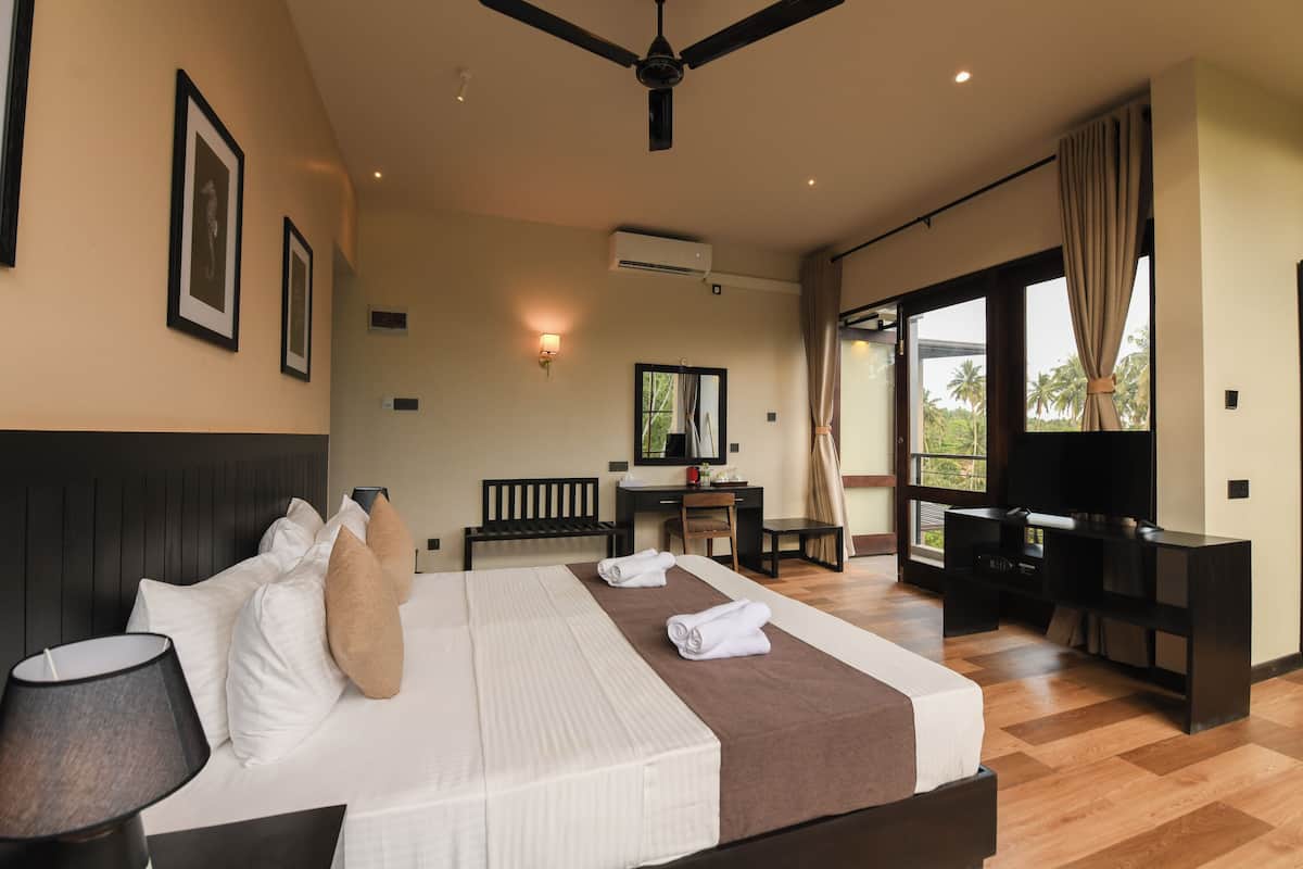 Habitació d'hotel amb llit, escriptori, televisió i grans finestres.