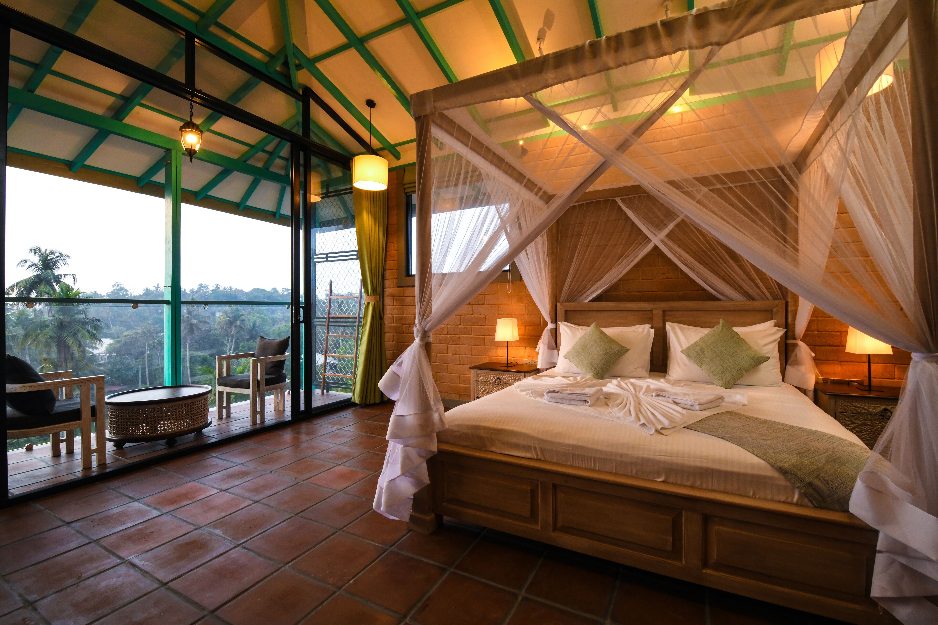 Una habitación amplia con una cama grande, vistas al exterior y un balcón con sillas.