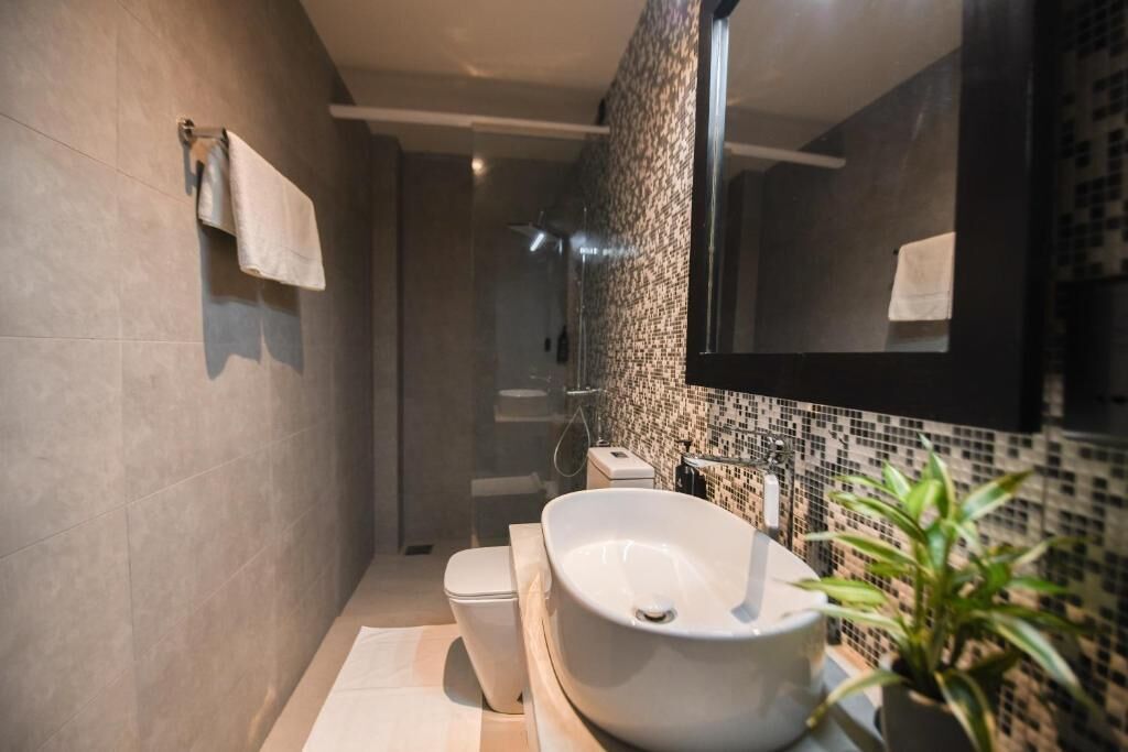 A modern bathroom with a large sink, toilet, and a mirror.