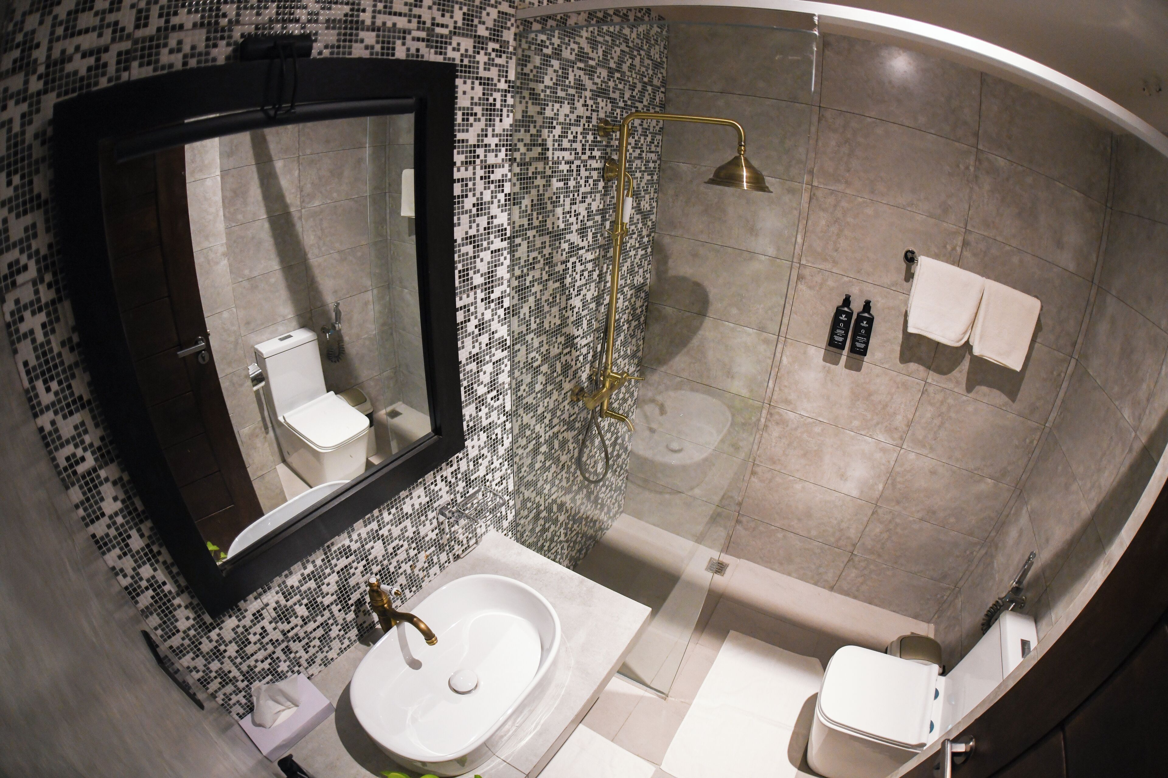 Une salle de bain avec un lavabo blanc, des toilettes, une douche dotée d’une porte en verre et un miroir.