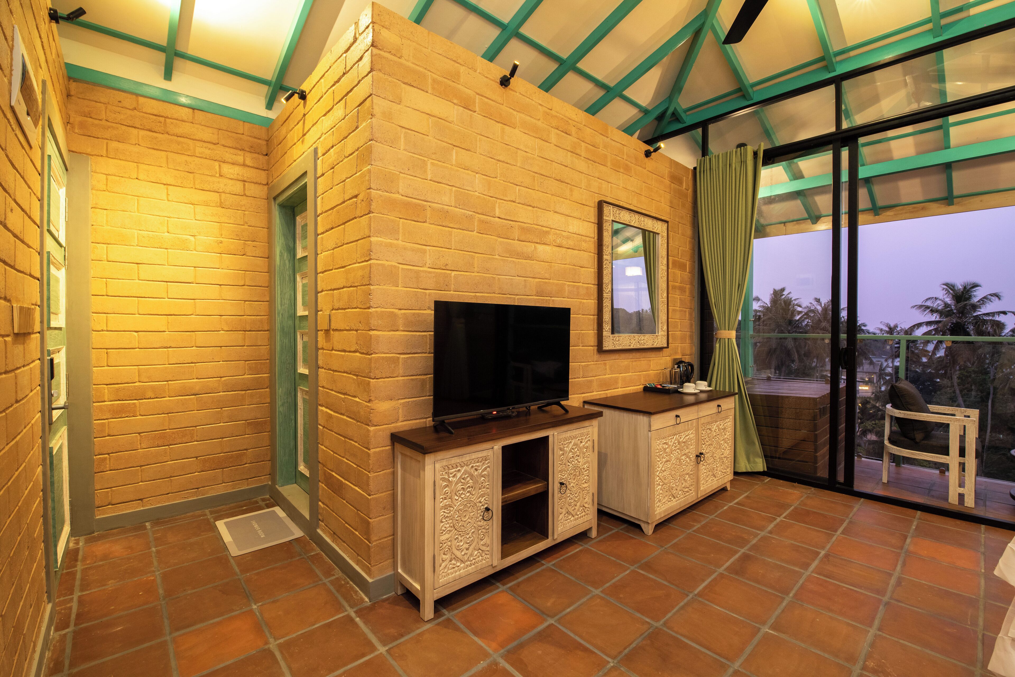 A room with a brick wall, a flat-screen TV, a cabinet, and a sliding glass door leading to an outdoor area.