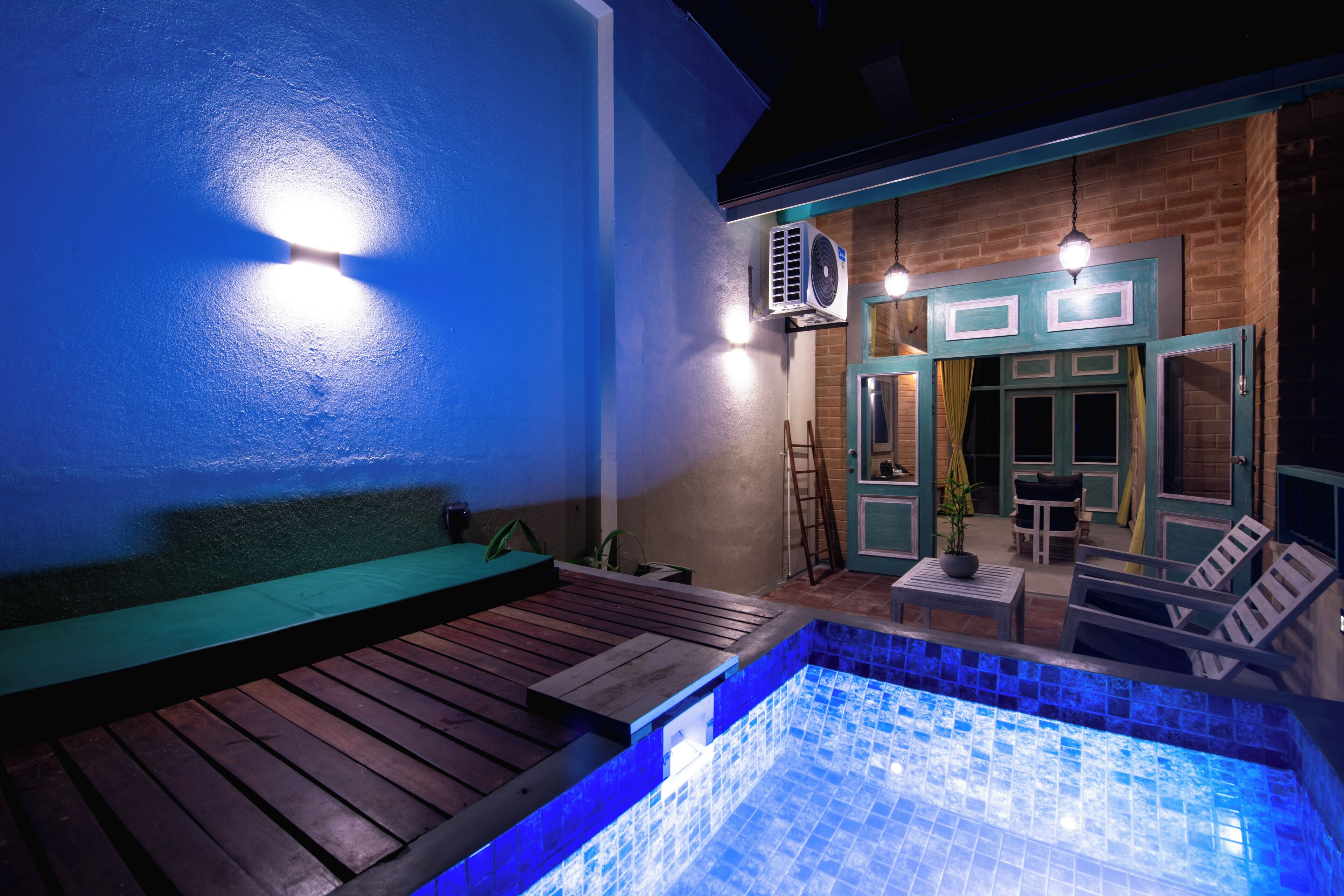 A pool area with a wooden deck, a lounge chair, and a small table.