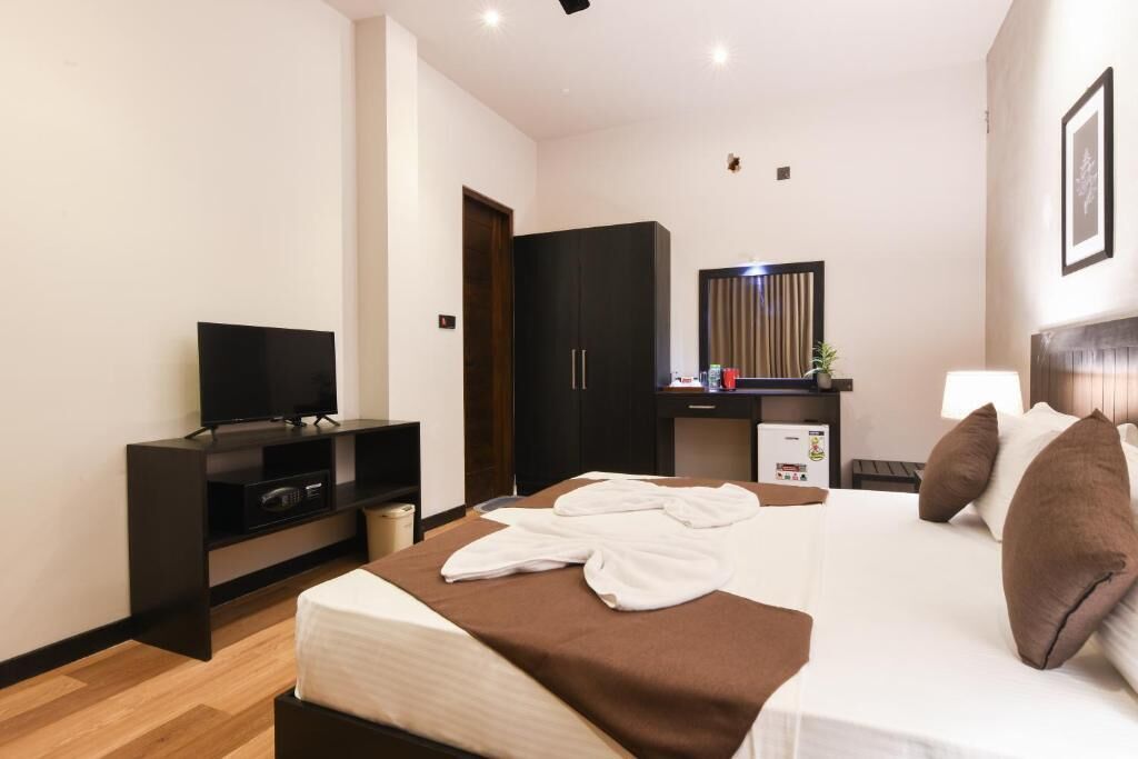 Una habitación de hotel moderna con una cama, un televisor, un armario y un escritorio con una lámpara.