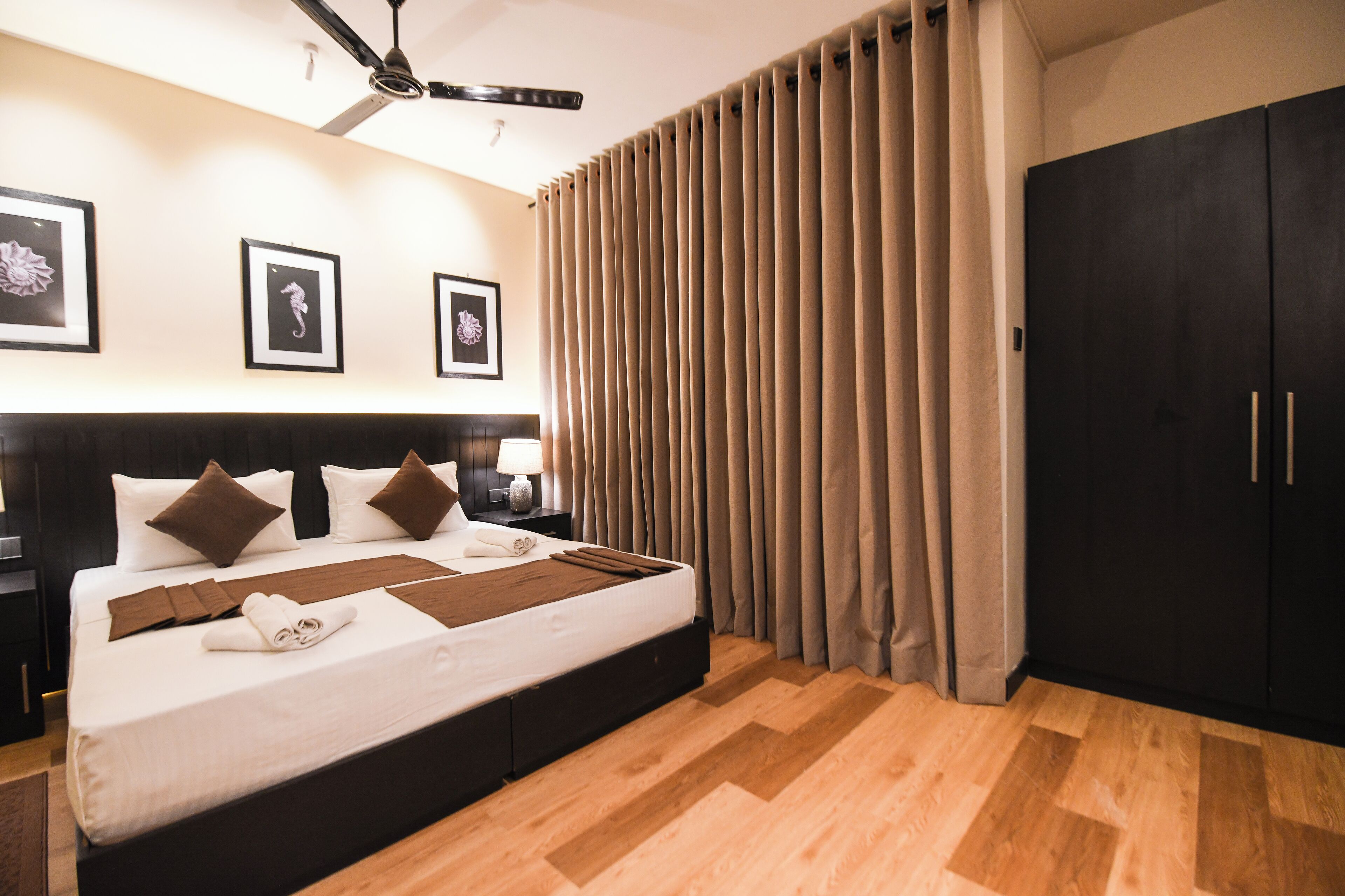 Una habitación de hotel con una cama grande, un armario y un ventilador de techo.