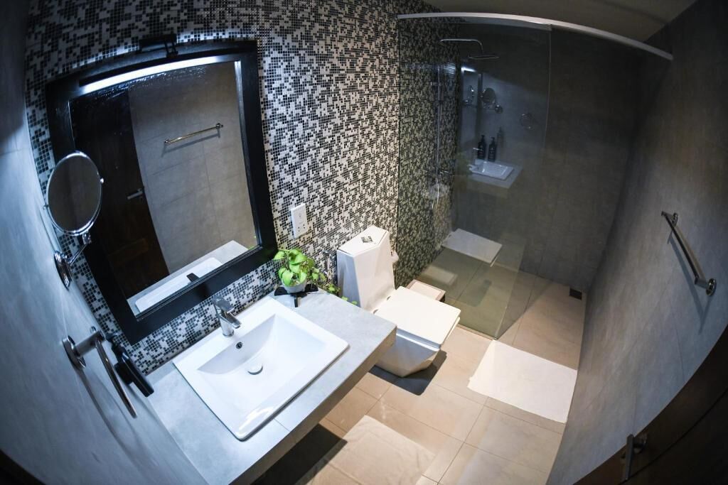 Un baño moderno con un espejo grande, lavamanos blanco y cabina de ducha con paredes de vidrio.
