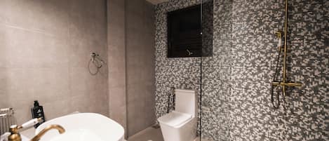 Un baño moderno con una bañera independiente, inodoro y cabina de ducha.