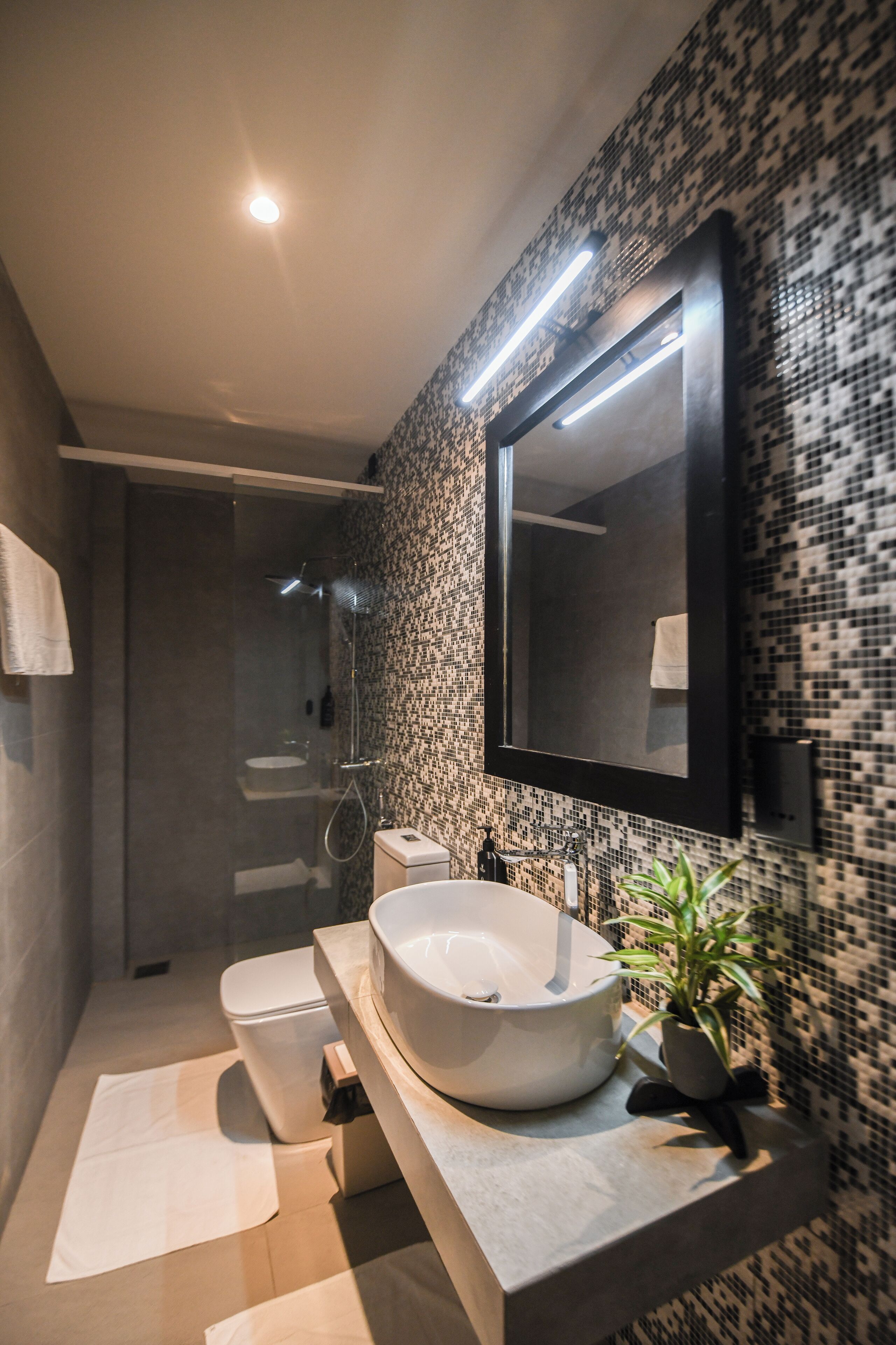 Un baño moderno con un espejo grande, un lavamanos sobre encimera y una zona de ducha.