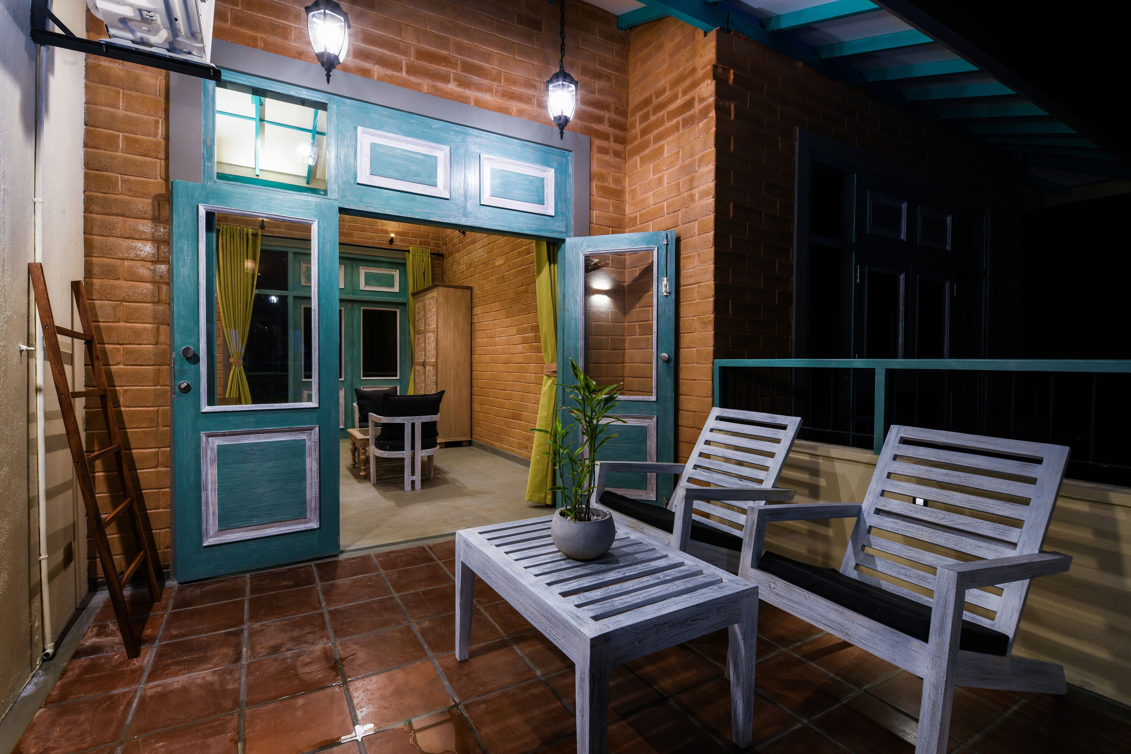Un patio al aire libre con pared de ladrillo, banco de madera, mesa y planta en maceta.