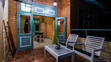 An outdoor patio area with a brick wall, a wooden bench, a table, and a potted plant.