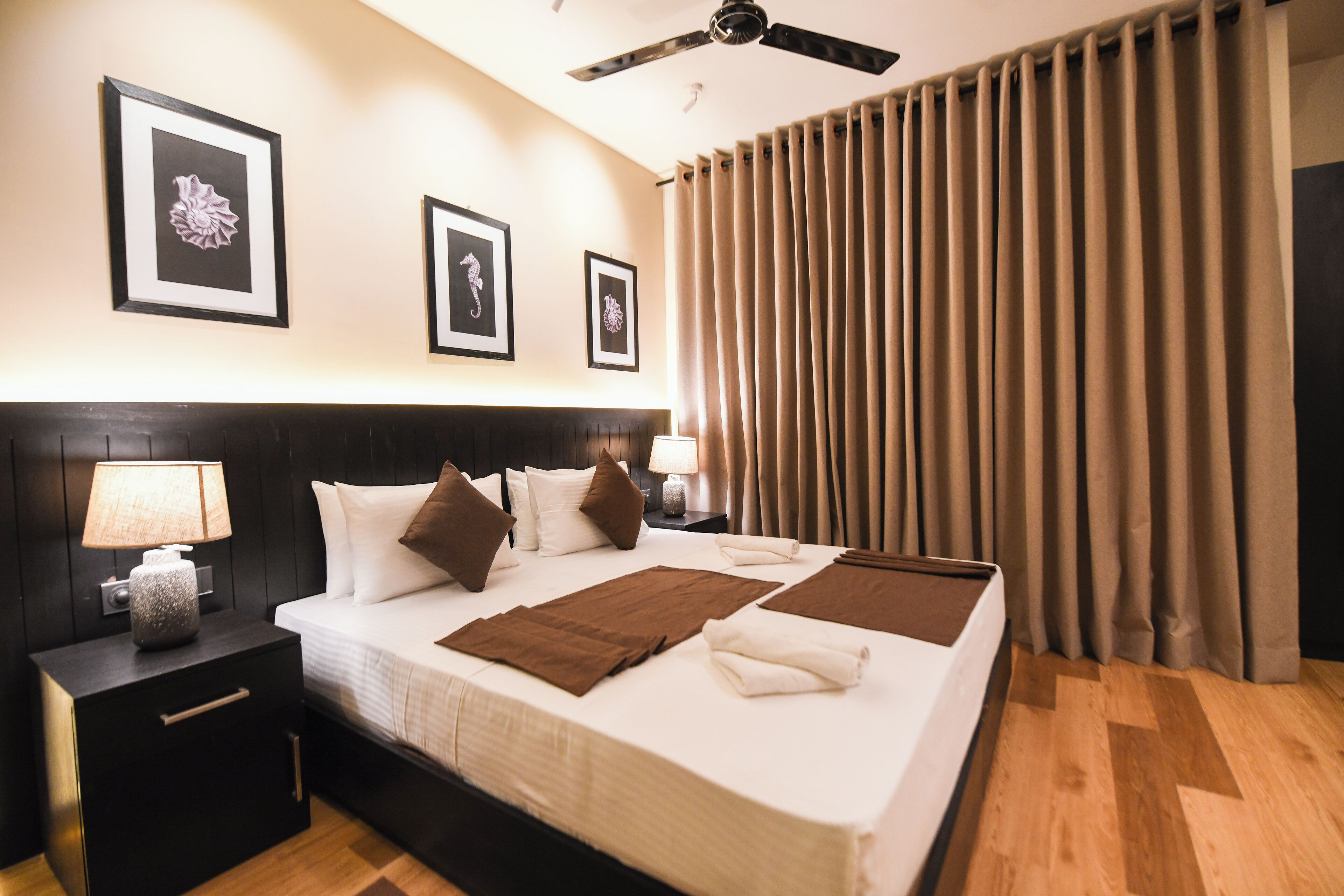 Una habitación de hotel con una cama grande, una mesita de noche con lámpara y cuadros en la pared.