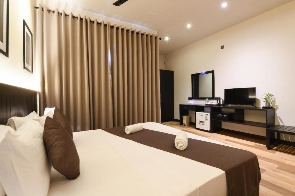 Habitación de hotel con cama, escritorio, televisor y espejo.
