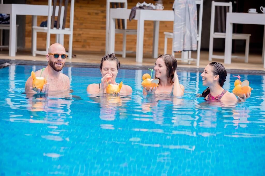 A swimming pool with four people holding orange drinks.