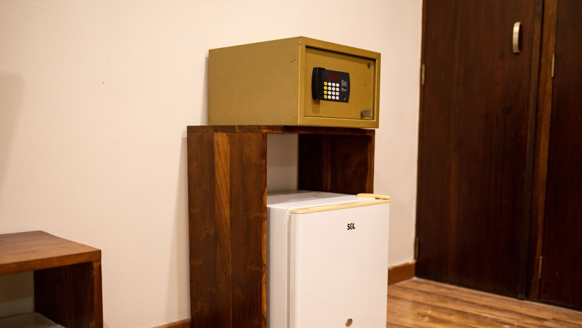 A small wooden cabinet with a white refrigerator on top.