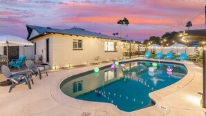A swimming pool with lounge chairs and a building with a sloped roof. - Luxury Gatsby Hideaway - Heated Pool, Hot Tub, Game Room, Fire Pit Near Old Town (Scottsdale)