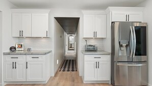 A modern kitchen with white cabinetry, a stainless steel refrigerator, and a black and white checkered floor. - Luxury Gatsby Hideaway - Heated Pool, Hot Tub, Game Room, Fire Pit Near Old Town (Scottsdale)