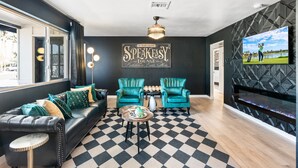 A modern lounge with a checkered floor, a fireplace, and a large TV screen. - Luxury Gatsby Hideaway - Heated Pool, Hot Tub, Game Room, Fire Pit Near Old Town (Scottsdale)
