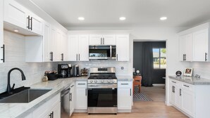 A modern kitchen with white cabinetry, a stainless steel stove, and a microwave. - Luxury Gatsby Hideaway - Heated Pool, Hot Tub, Game Room, Fire Pit Near Old Town (Scottsdale)