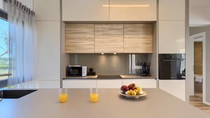 Een moderne keuken met een centraal kookeiland, een inbouwoven en een koffieapparaat.