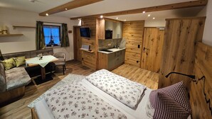 A compact bedroom with a bed, a desk, and a kitchenette. - Apartment Salzberg, for 2 persons, 30sqm (Schönau am Königssee)