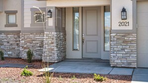 A modern house with a stone facade, a gray door, and the year 2021 displayed above the door.