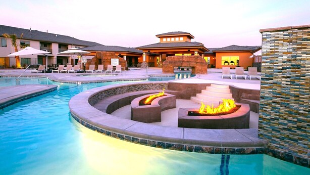A pool area with lounge chairs, a fire pit, and a building with a unique architectural design.