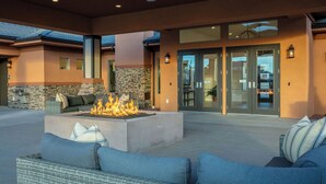 A modern outdoor seating area with a fire feature, stone wall, and a large glass door entrance.