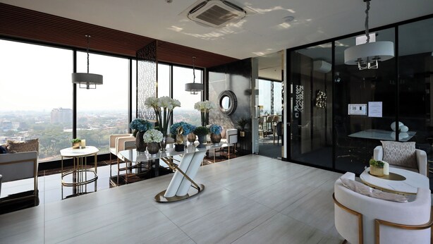 A modern interior with a large window, a round table with chairs, and a sofa. - Luxury Astra Sky River Apartment (Chang Wat Chiang Mai)