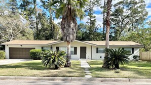 A single-story house with a garage, a front yard with palm trees, and a clear sky. - Spacious 4-bedroom house with Covered Private Pool in Gainesville (Gainesville)