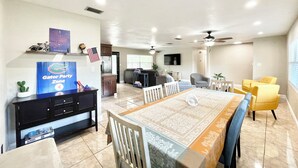 A spacious living room with a dining area, a kitchen, and a TV mounted on the wall. - Spacious 4-bedroom house with Covered Private Pool in Gainesville (Gainesville)