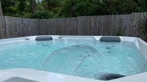 A hot tub with a control panel, surrounded by a wooden fence and greenery. - Spacious 4-bedroom house with Covered Private Pool in Gainesville (Gainesville)