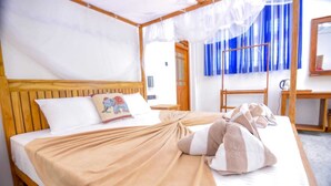 A neatly made bed with a beige blanket, a pillow with an elephant design, and a canopy overhead. - River Cottage Wellawaya (Wellawaya)