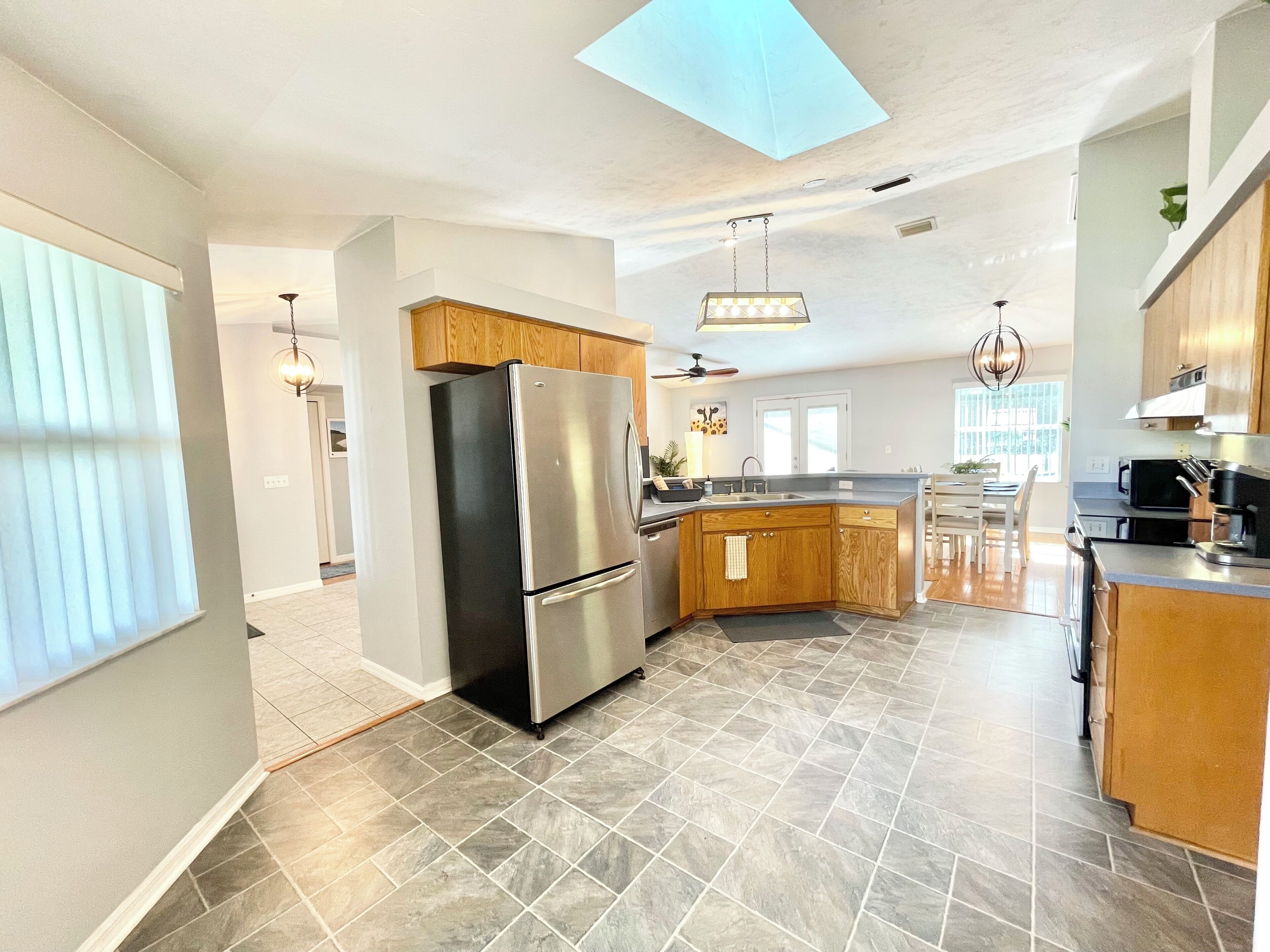 Une cuisine moderne dotée d’un réfrigérateur en acier inoxydable, de meubles en bois et d’un grand îlot central.