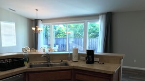 A kitchen with a built-in dishwasher, a sink, a coffee maker, and a window with a view of a backyard. - Charming 3-bedroom house with AC and WiFi in Santa Rosa (Santa Rosa)