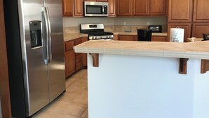 A kitchen with wooden cabinets, a stainless steel refrigerator, a microwave, and a stove. - Charming 3-bedroom house with AC and WiFi in Santa Rosa (Santa Rosa)