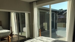 A bedroom with a large bed, a wooden headboard, and a view of the backyard through a sliding glass door. - Charming 3-bedroom house with AC and WiFi in Santa Rosa (Santa Rosa)