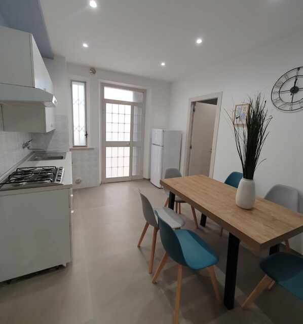 A modern kitchen with a gas stove, a dining table with chairs, and a large window.