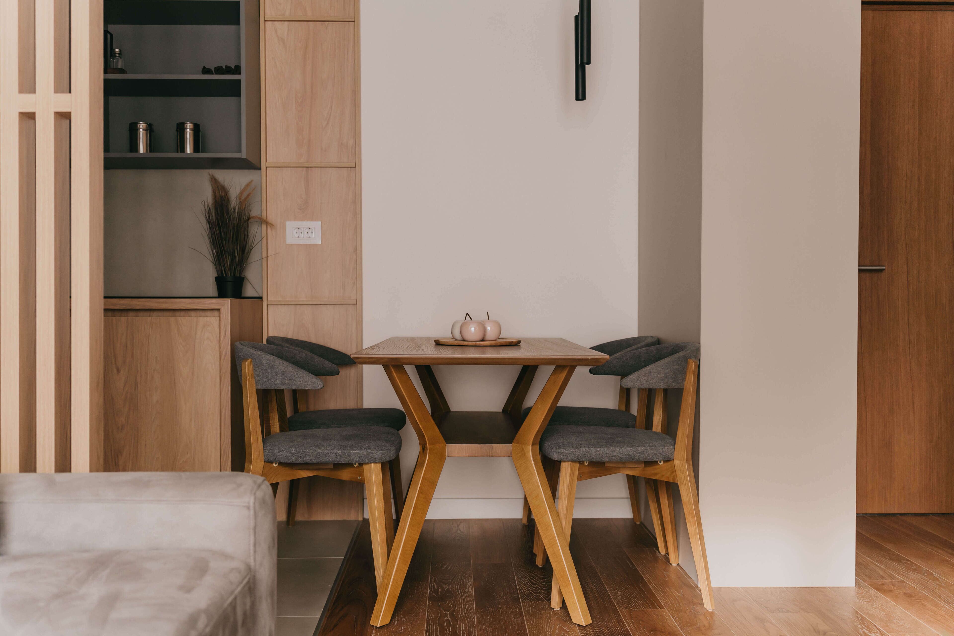 Une cuisine moderne avec une table et des chaises en bois, une étagère intégrée et une plante en pot.