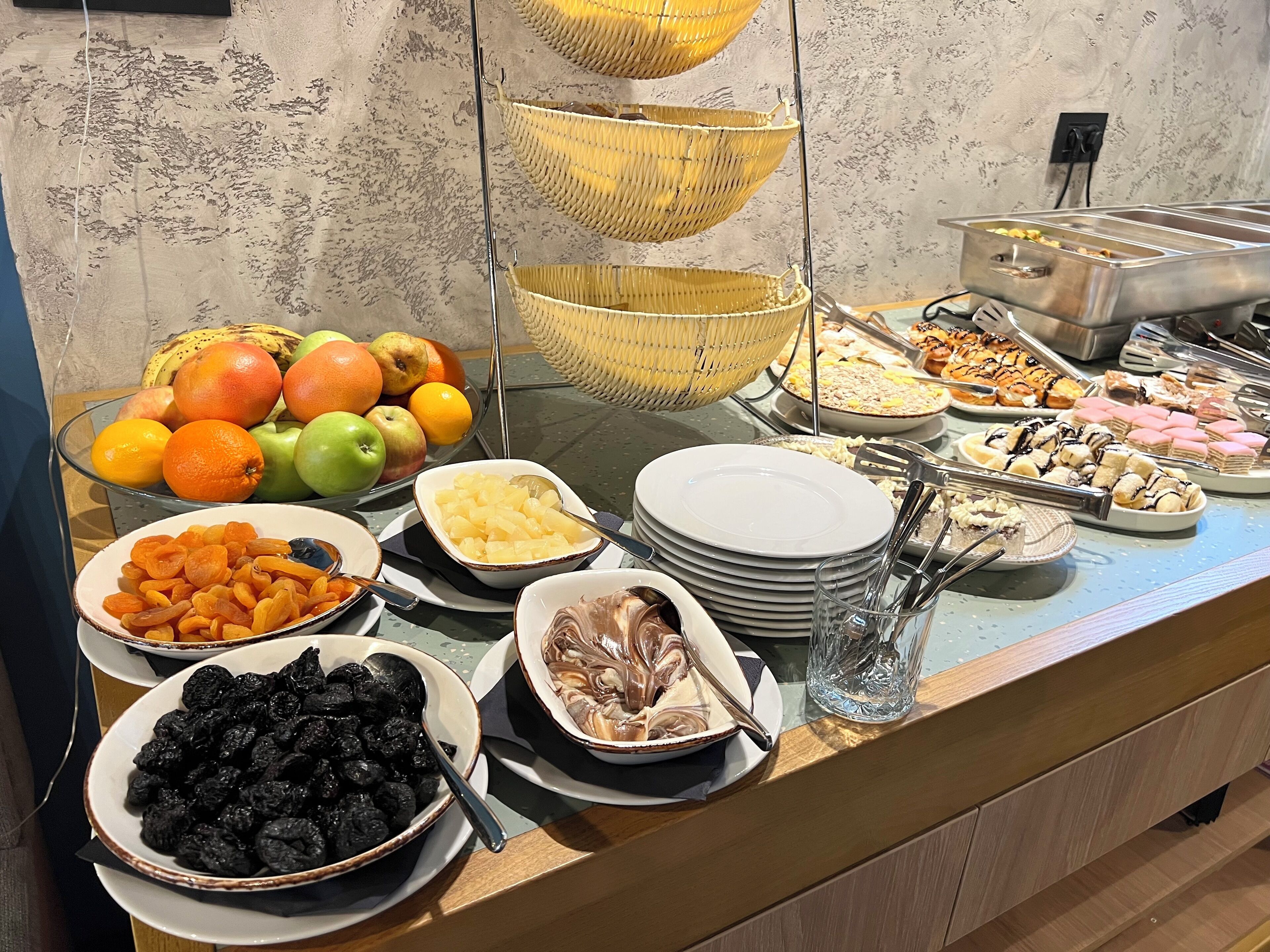 A buffet with various food items, including fruits, pastries, and desserts.