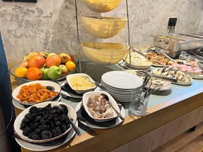 Un bufé con diferentes opciones de comida, incluyendo frutas, pasteles y postres.