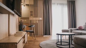 A modern living room with a wooden floor, a round coffee table, a sofa, a chair, and a bookshelf. - Safran Zlatibor (Zlatibor)