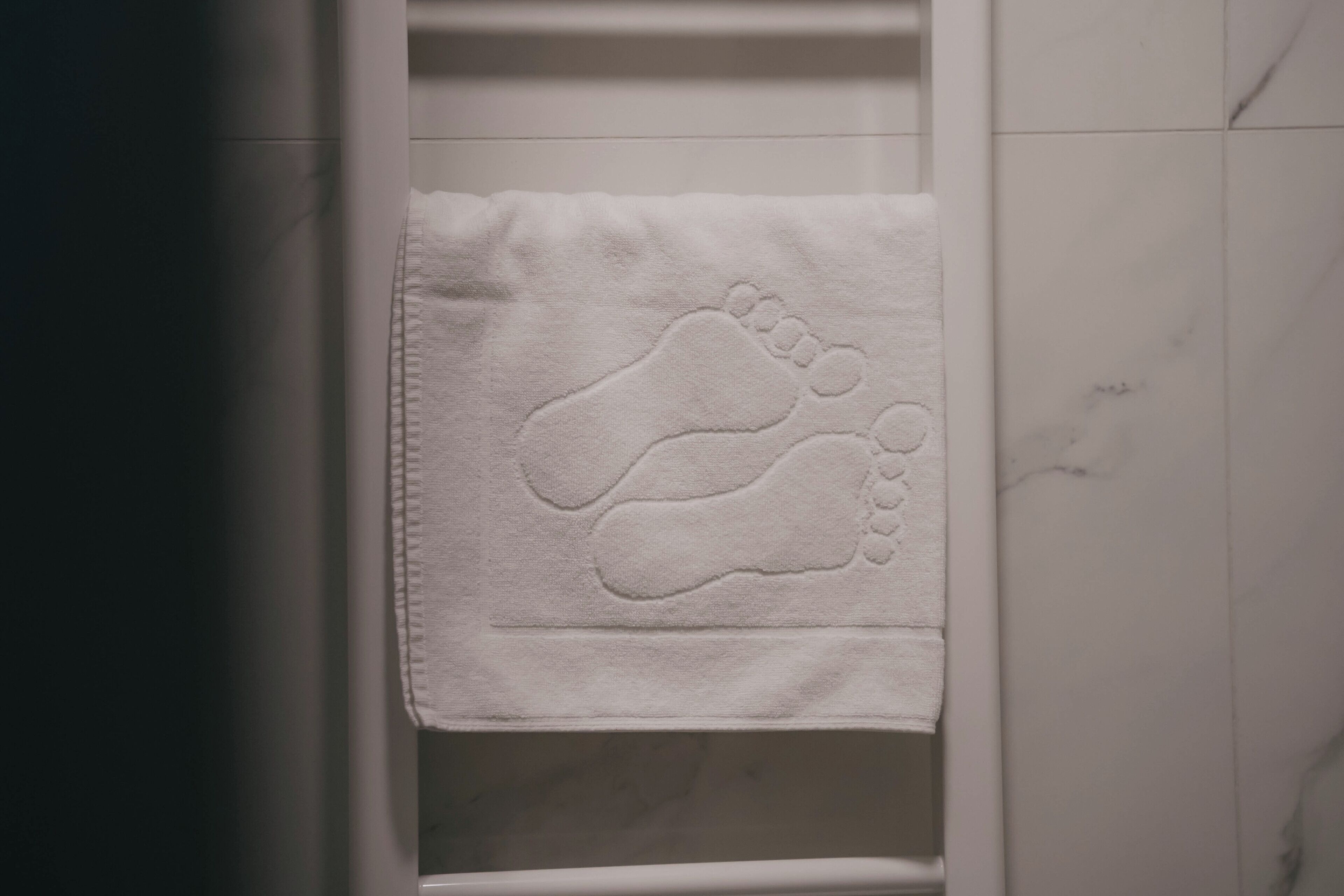 A white towel with a footprint design hanging on a white wall.