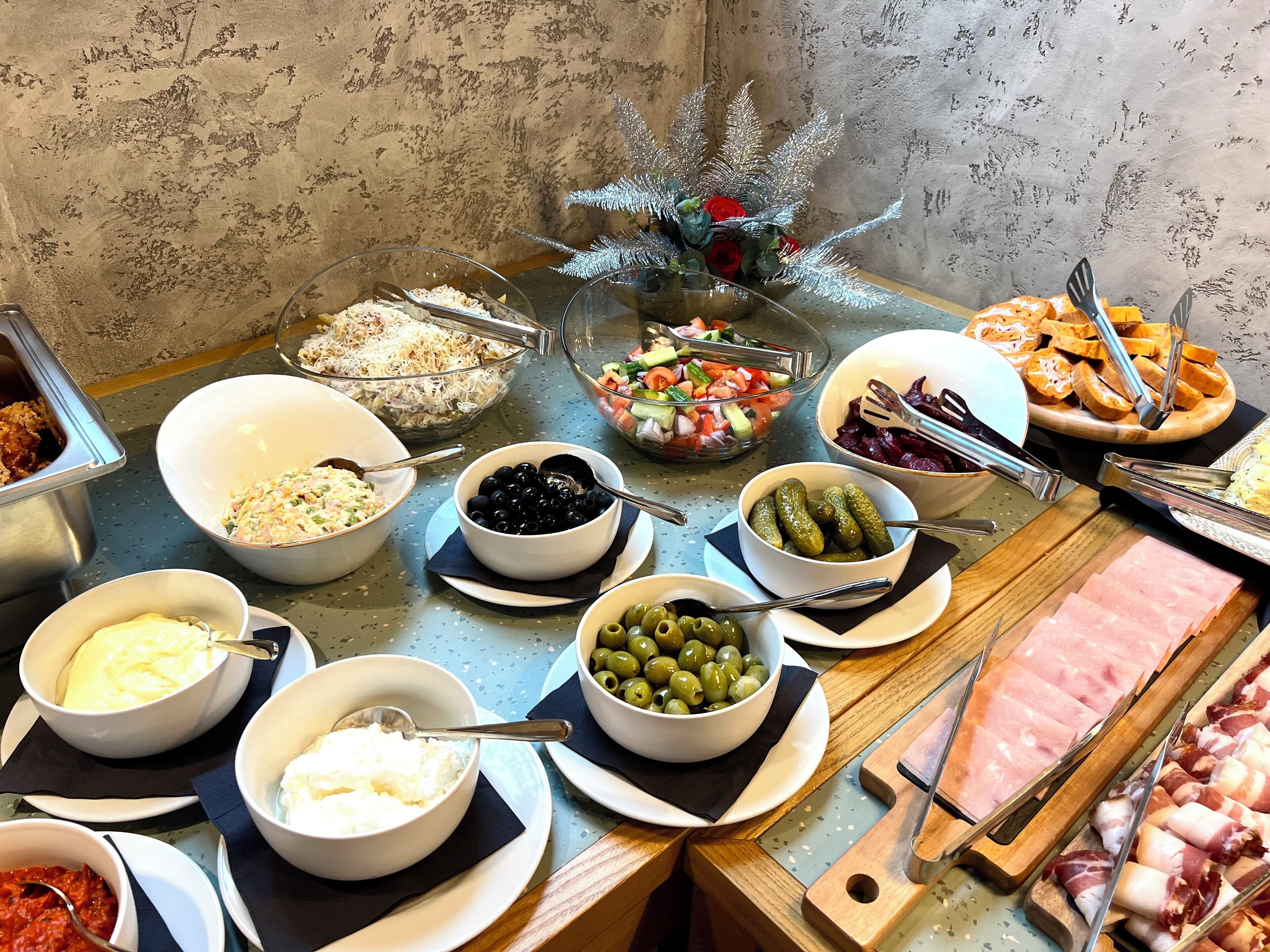 Una mesa de buffet con diferentes opciones de comida, incluyendo ensaladas, aceitunas y carnes.