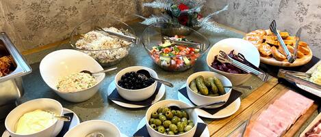 Una mesa de buffet con diferentes opciones de comida, incluyendo ensaladas, aceitunas y carnes.