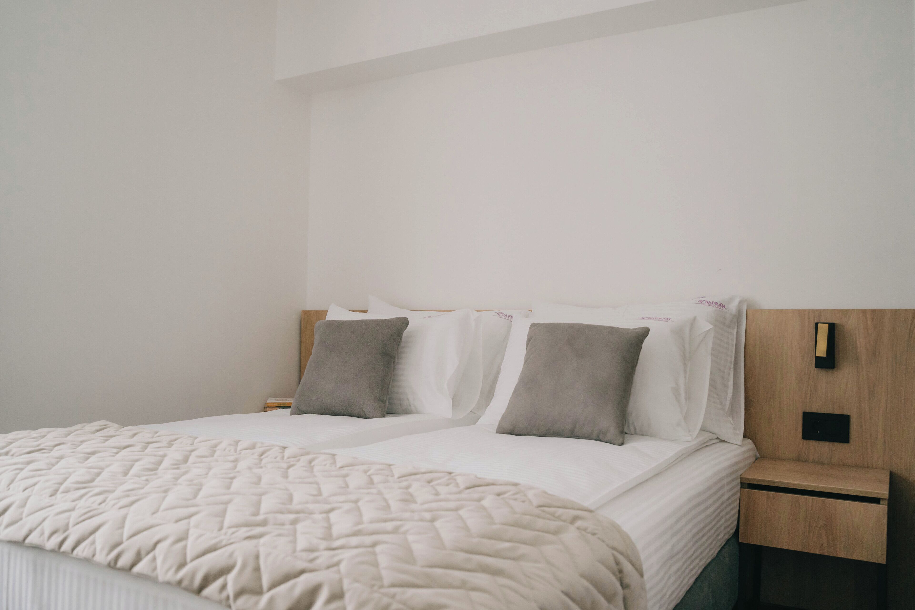 A neatly made double bed with a quilted blanket, two pillows, and a wooden headboard.