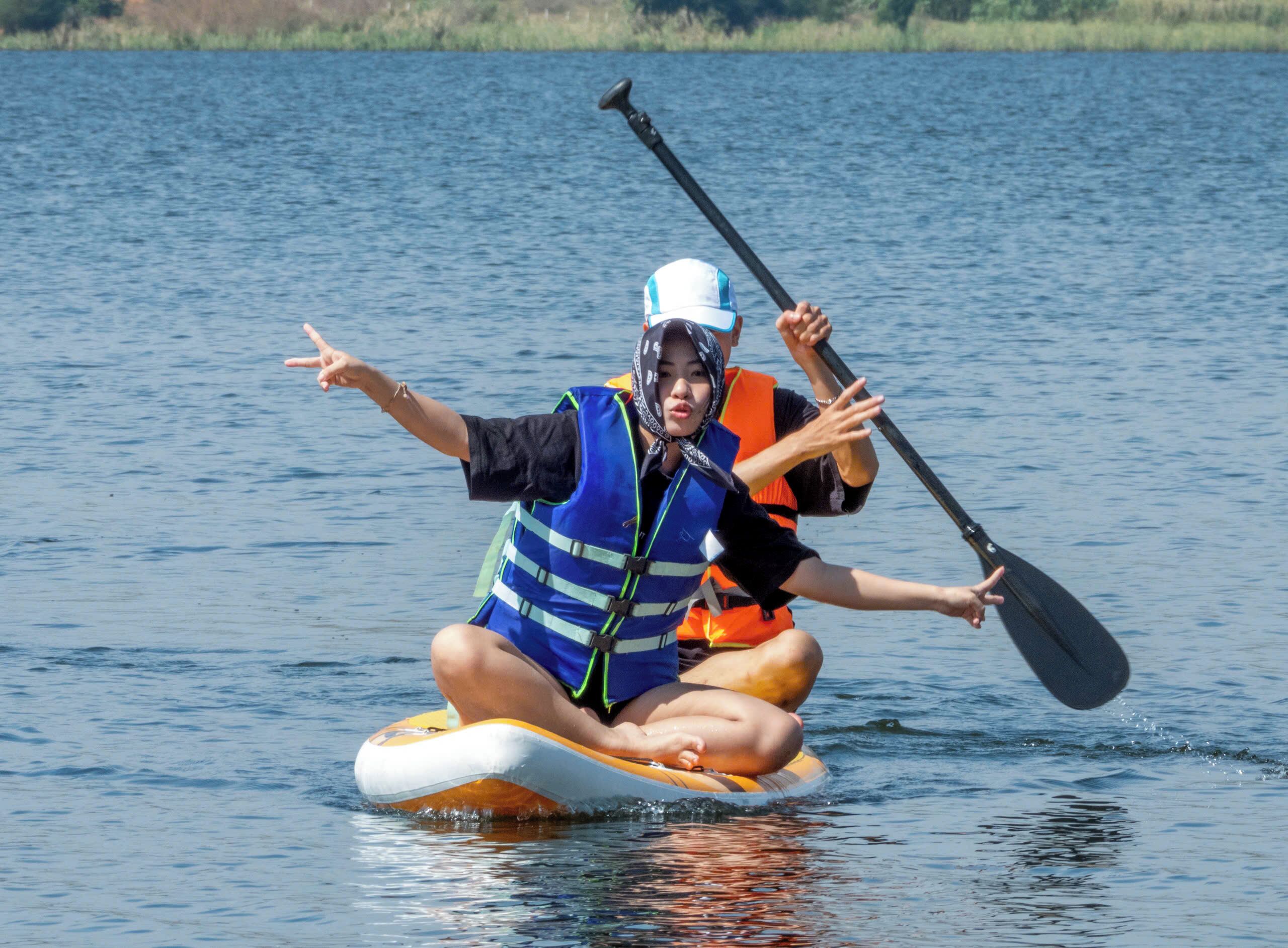 A person sitting on a paddleboard in a body of water.