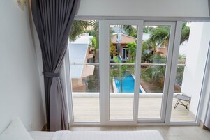 A room with a large sliding glass door leading to an outdoor area with a pool and greenery.