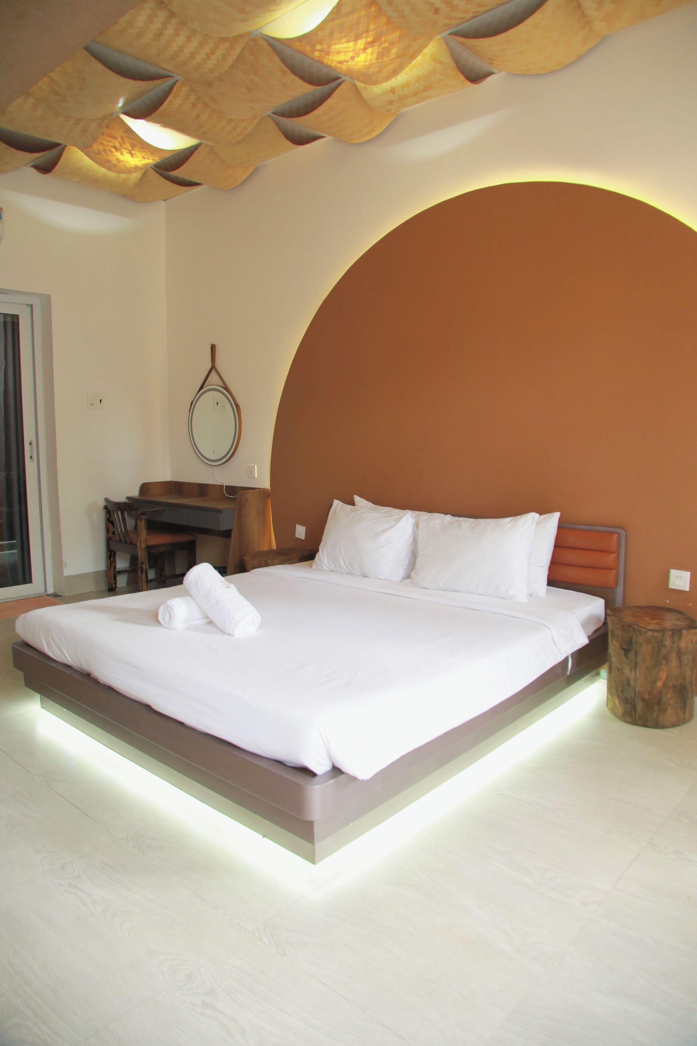 Une chambre d’hôtel moderne avec un grand lit, un bureau et un miroir au mur.