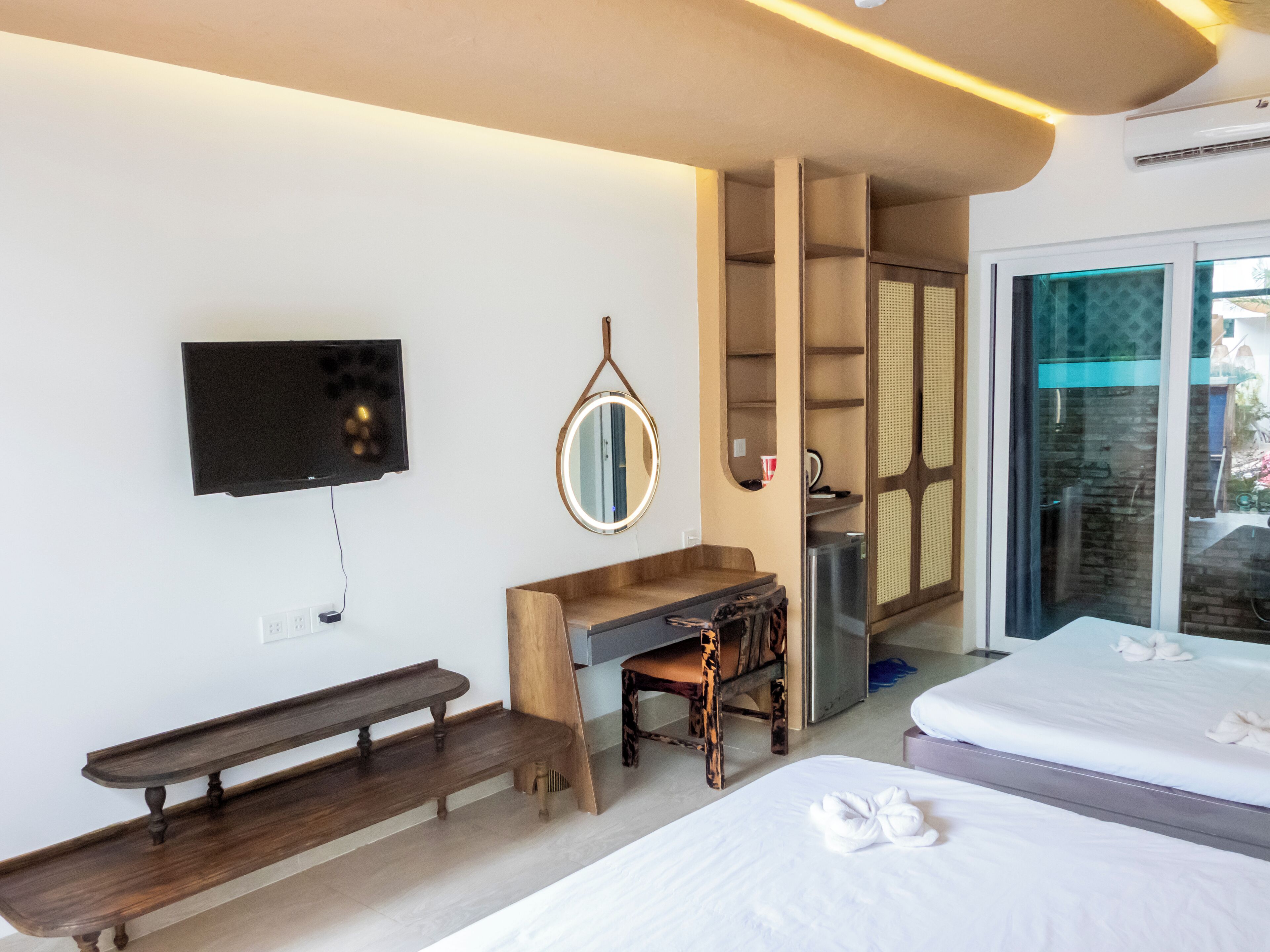 Una habitación de hotel con una cama, un escritorio, una silla, un televisor y un espejo.